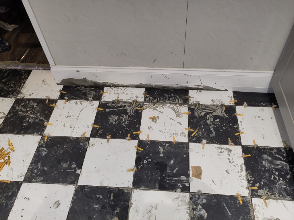 More black and white tiles with wall in the background.