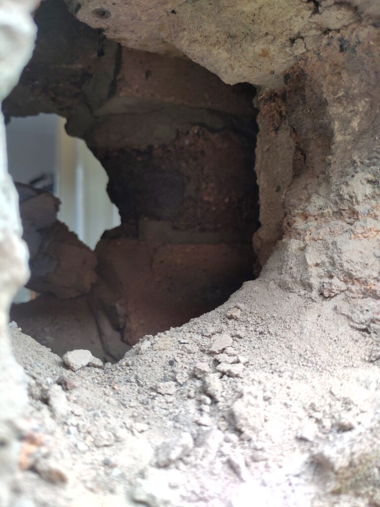 View through hole in the wall where the flue was, can see the cavity with no sign of insulation.