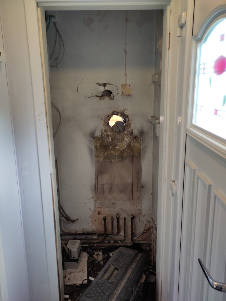 Plant room with the gas boiler removed. Can see the hole in the wall for the gas boiler flue and the pipes that once connected to the boiler.